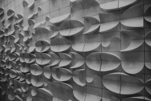 Foto preto e branca de uma parede com formatos tridimensionais que remetem ao mar, peixe e praia.